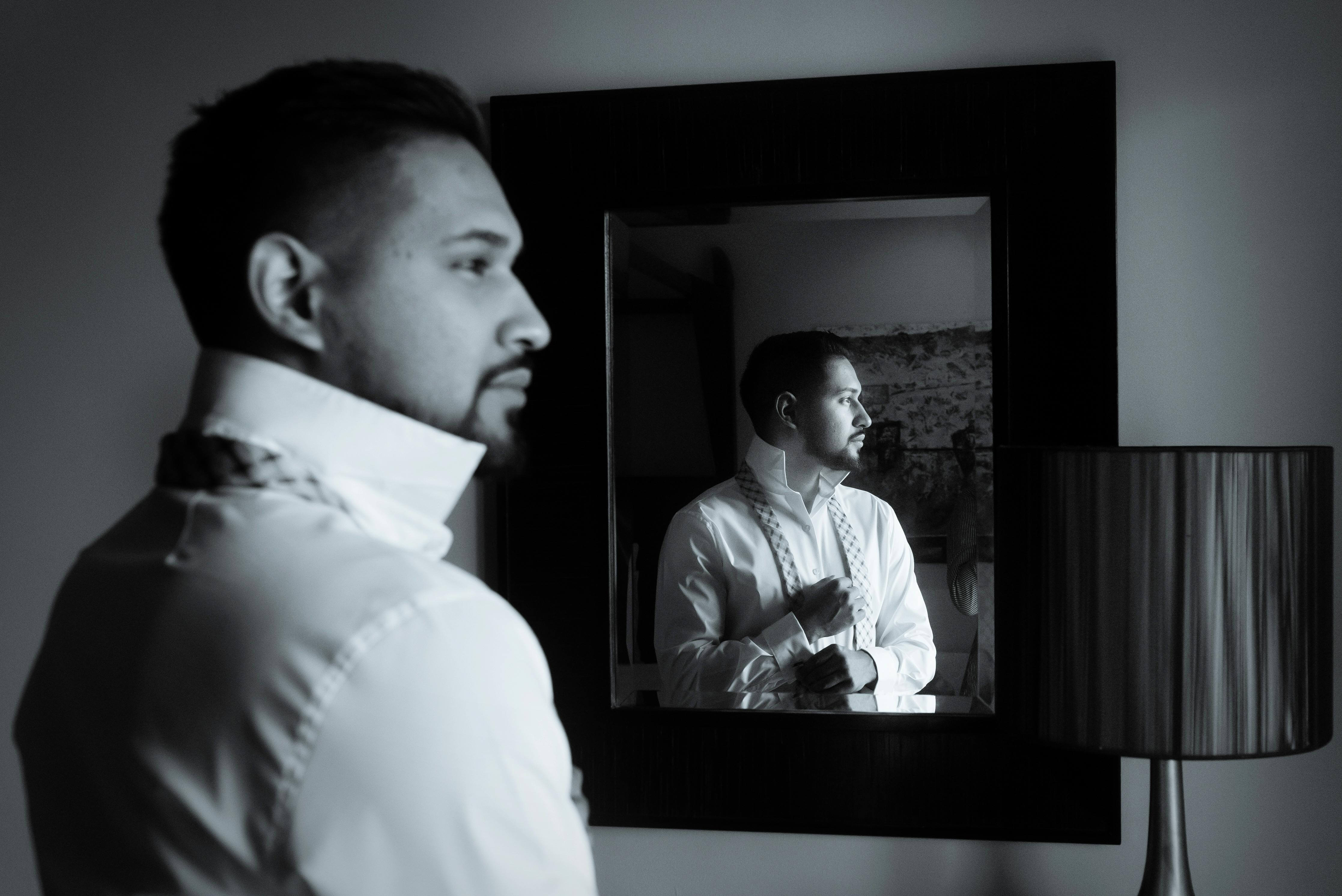 an attractive man getting ready in front of a mirror