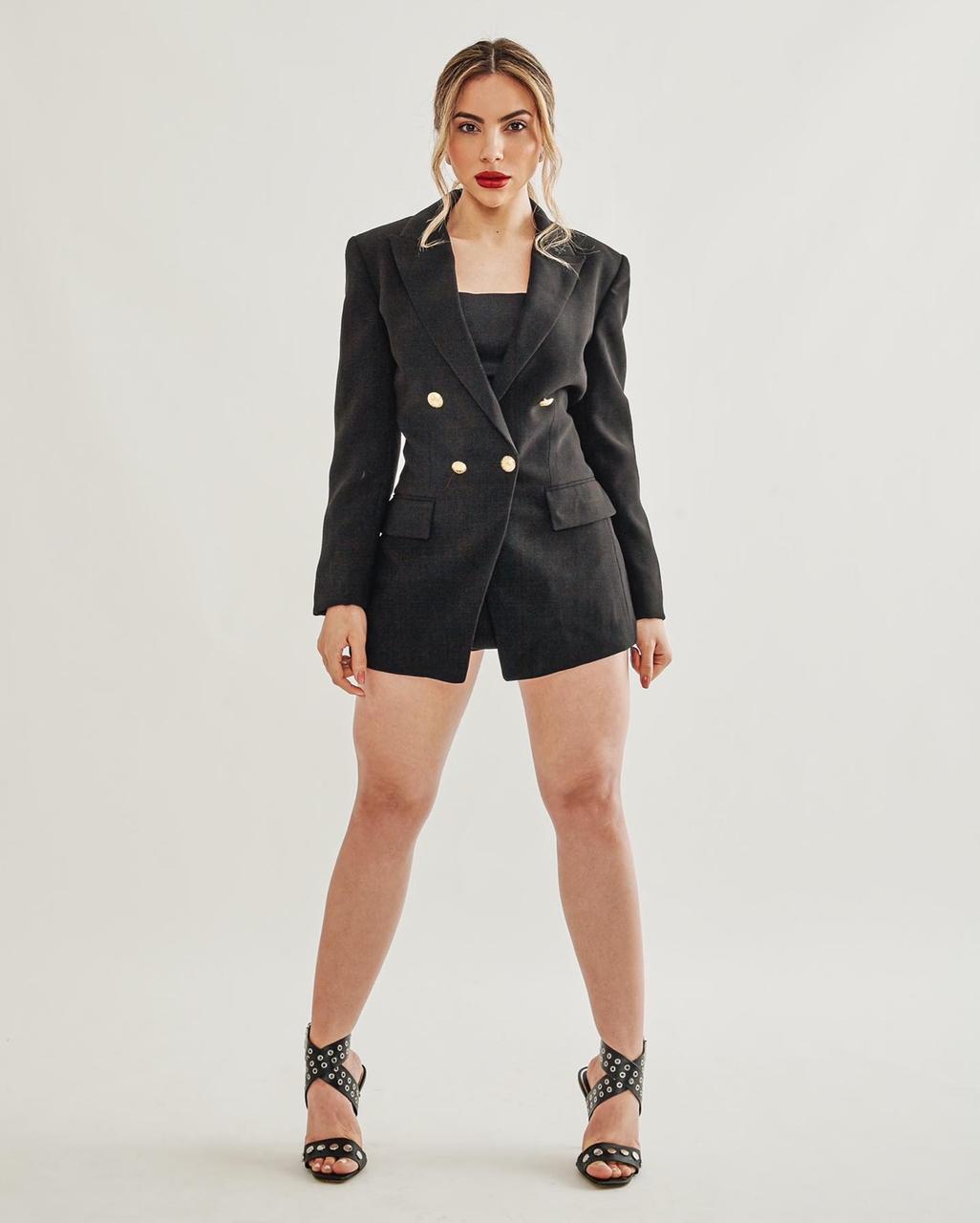 Mari standing in a black blazer top/dress 