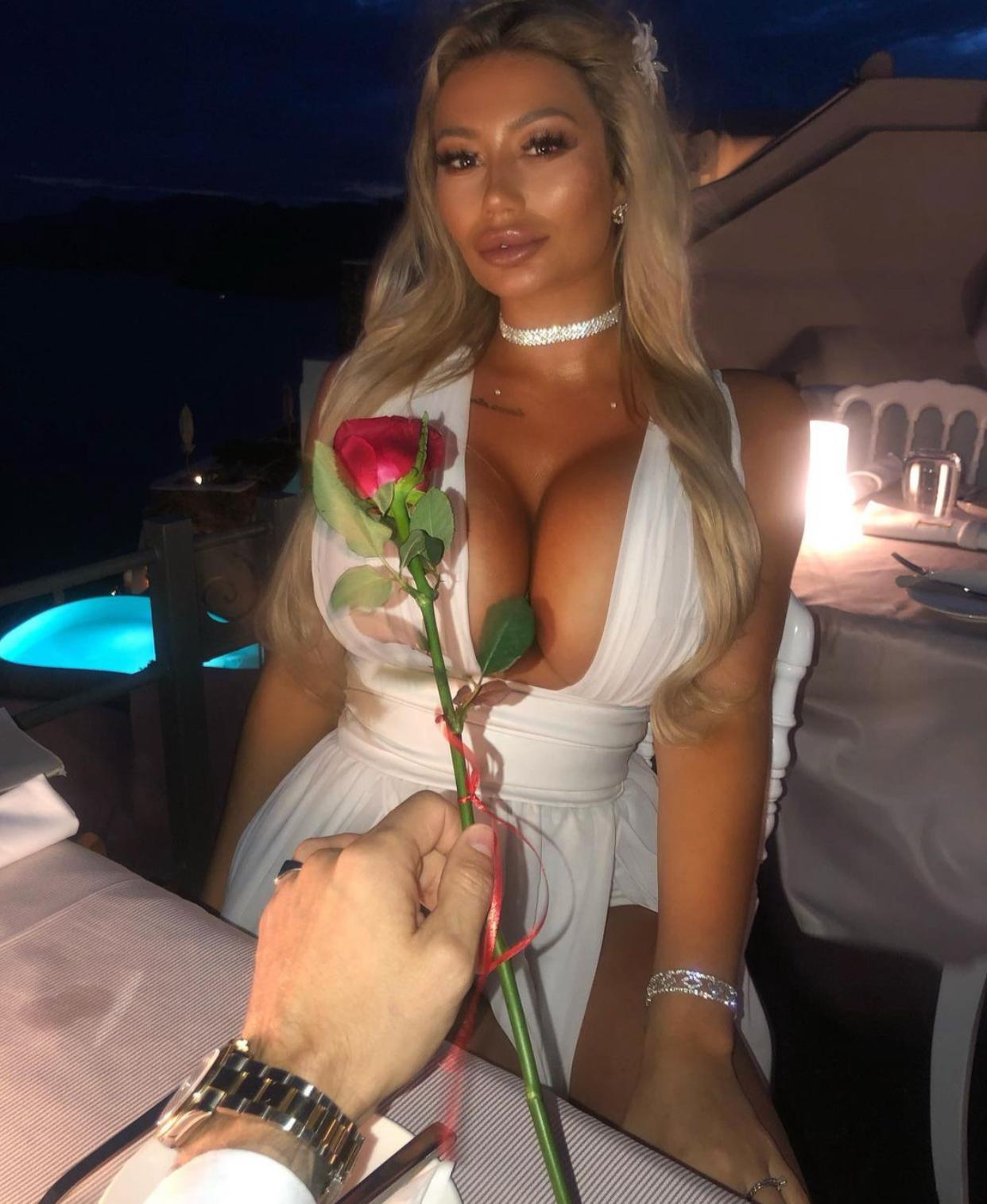 Sophie wearing a blue dress with a rose being offered to her 
