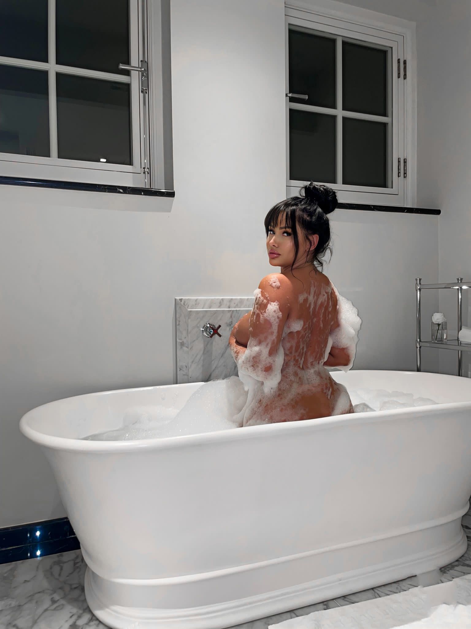Kara Lina naked in a bath-tub, looking back at you 