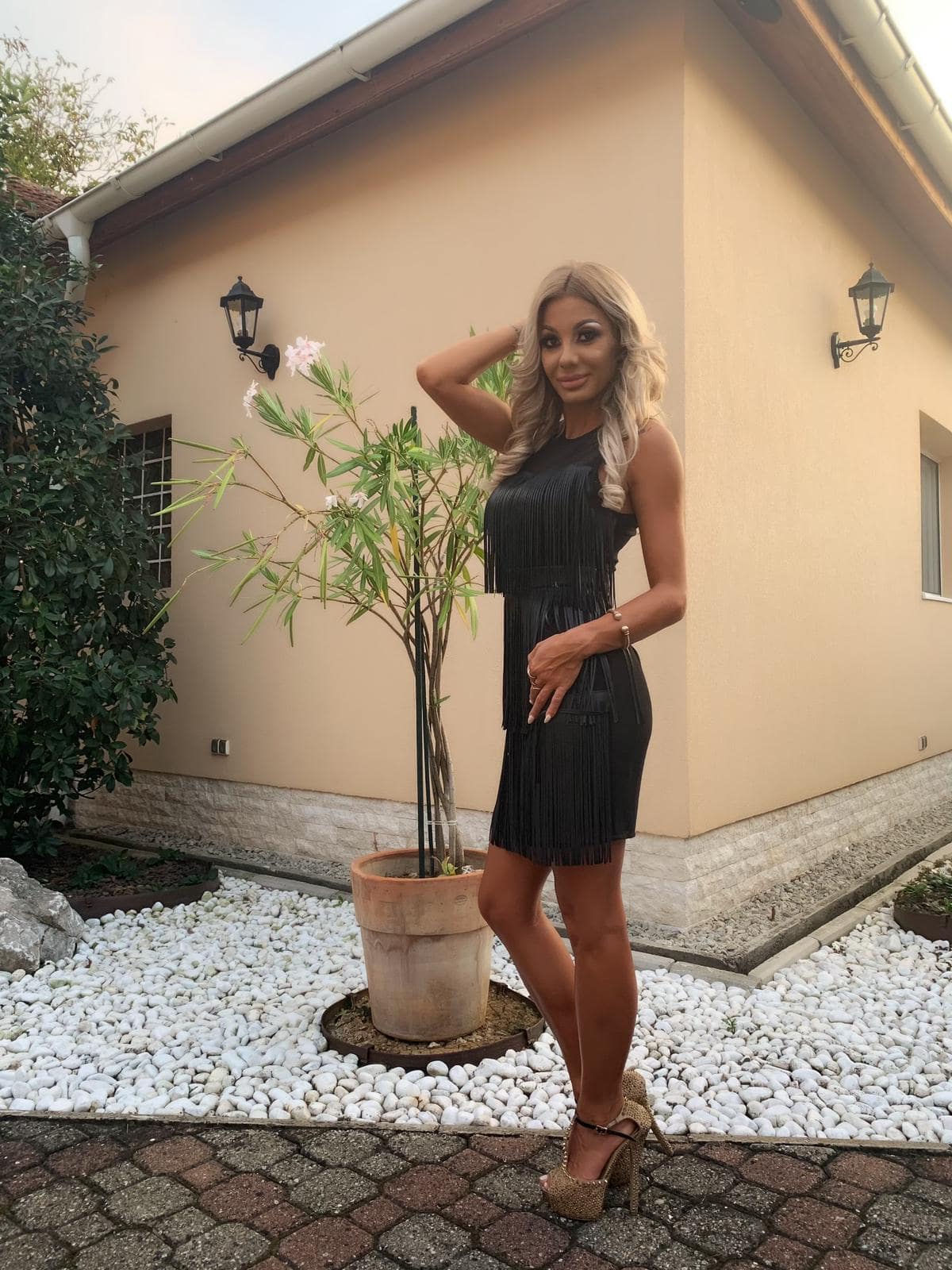 Alice standing in a black dress in front of a house 
