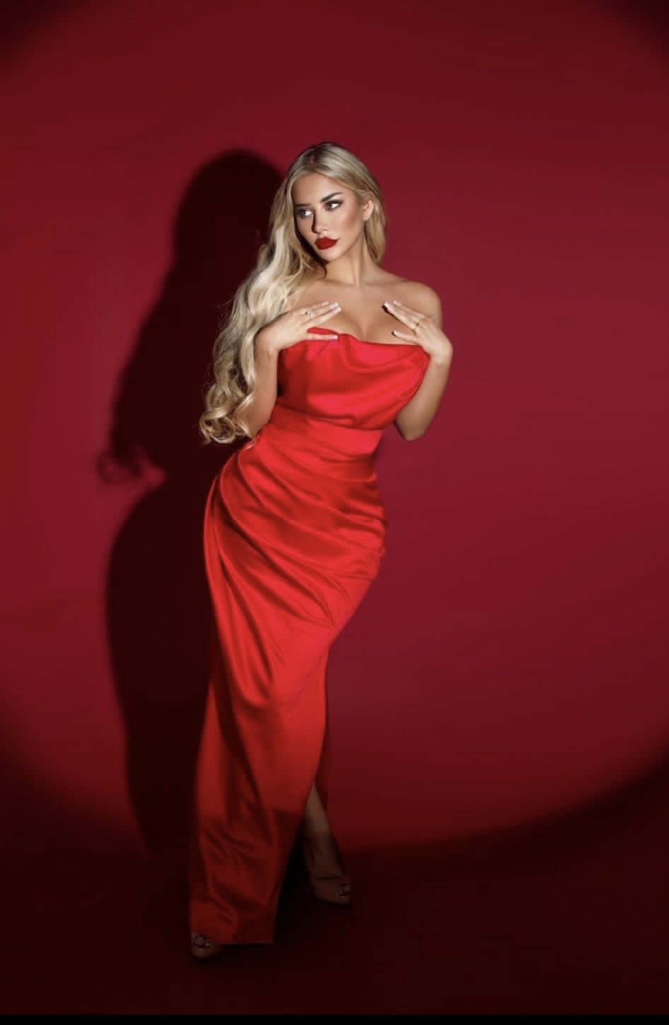 Scarlett standing in a lavish red dress 