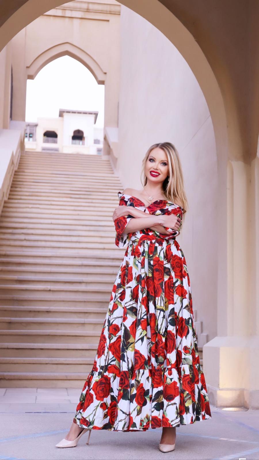 Joanna Bujoli standing infront of some stairs while wearing a large summer dress 