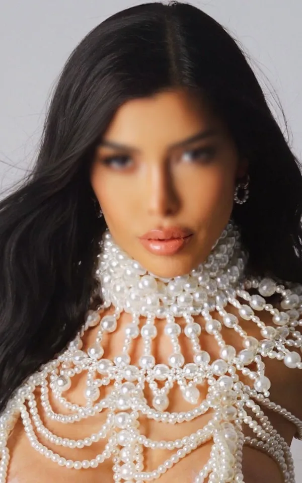 Adriana standing in a large pearly necklace 