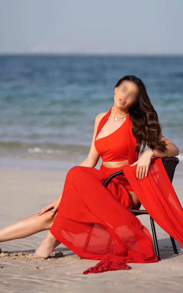 Anara sitting in a lavish red dress on the beach 