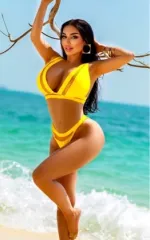 Leila getting out of the water at the beach while wearing a bright yellow set of swimwear 