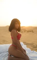 Melanie kneeling down while enjoying a picnic in the sand 