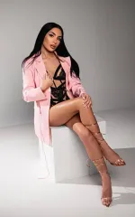 Mady sitting down in a set of black lingerie and pink blazer