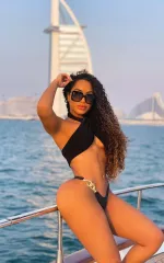 Izabelli sitting on the rail while on a yacht