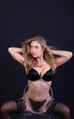Jayla sitting on a chair while showing off her boobs in a black bra 