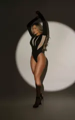 Amaya standing while wearing a black leotard