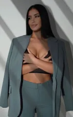 Aliya in a blue suit cupping her breasts in a black crop top